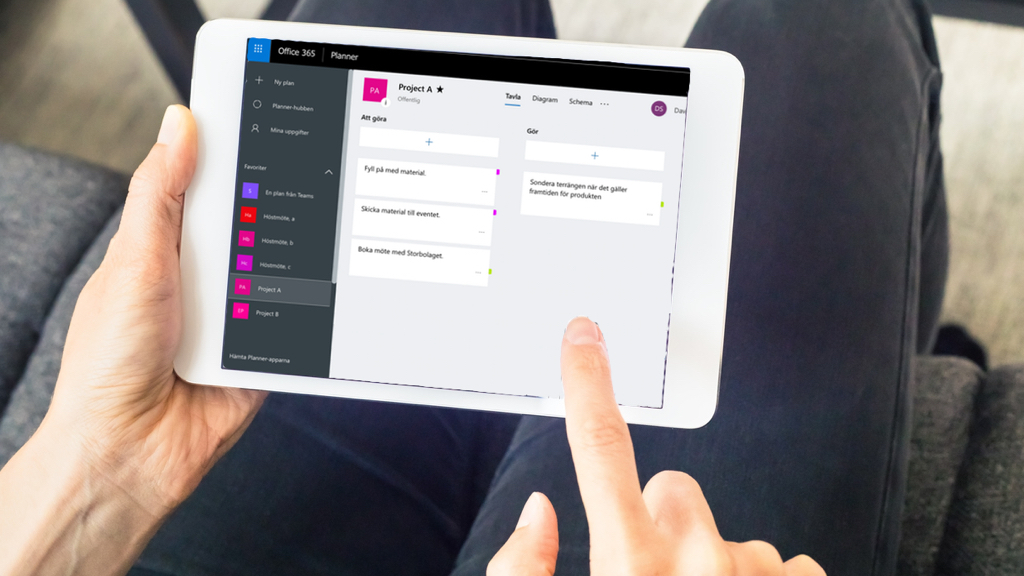 En person använder Microsoft Planner på en surfplatta för att hantera uppgifter för ett projekt.