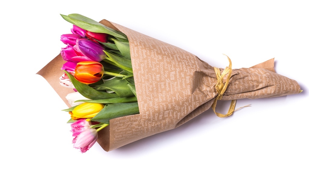 A colorful bouquet of tulips wrapped in brown paper.