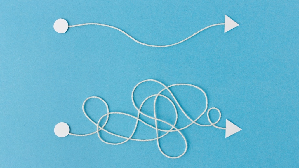 Two paths are depicted: one is straight and simple, while the other is tangled and complex, both leading to the same destination.