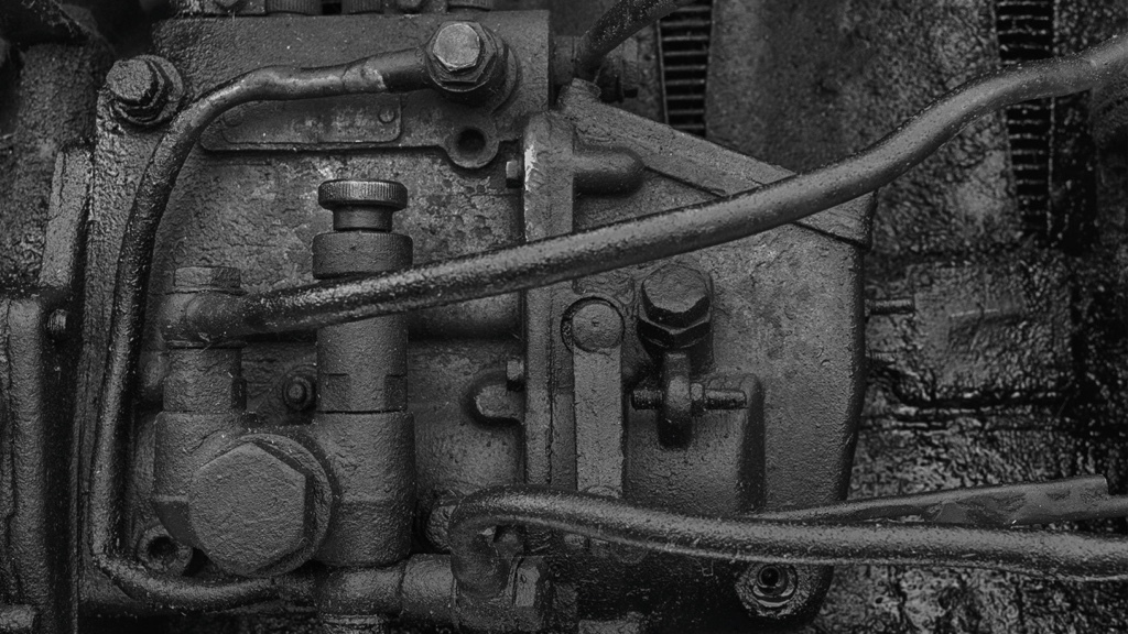 An old, greasy, and oily machine part with visible pipes and bolts.