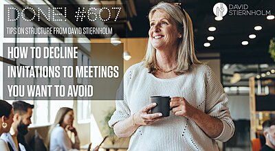 A smiling woman is holding a cup in a modern office environment, while people are having a meeting in the background.